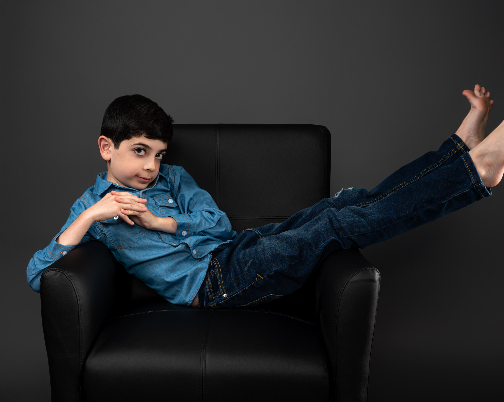 Young boy laying across chair
